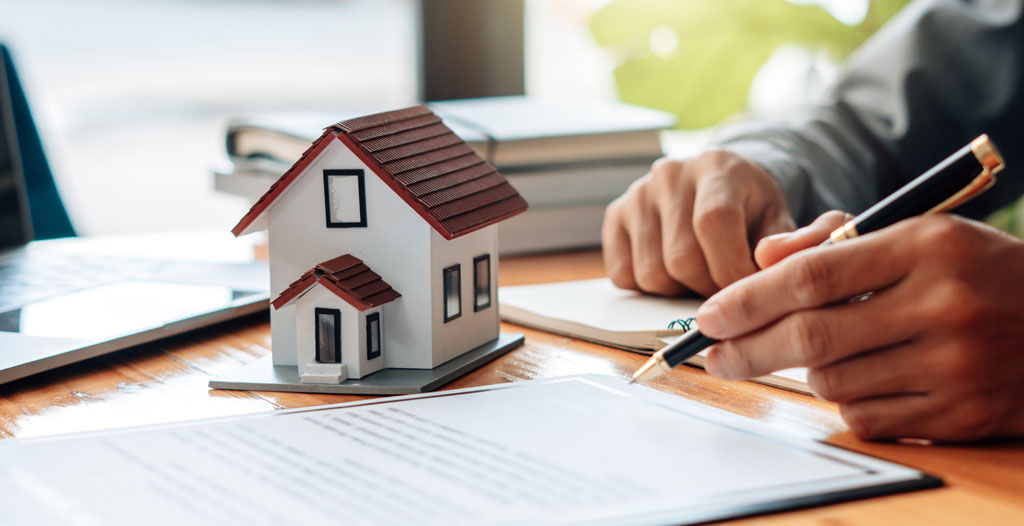 Gros plan sur des mains tenant un document contractuel avec des annotations au stylo, arrière-plan flou montrant une tasse